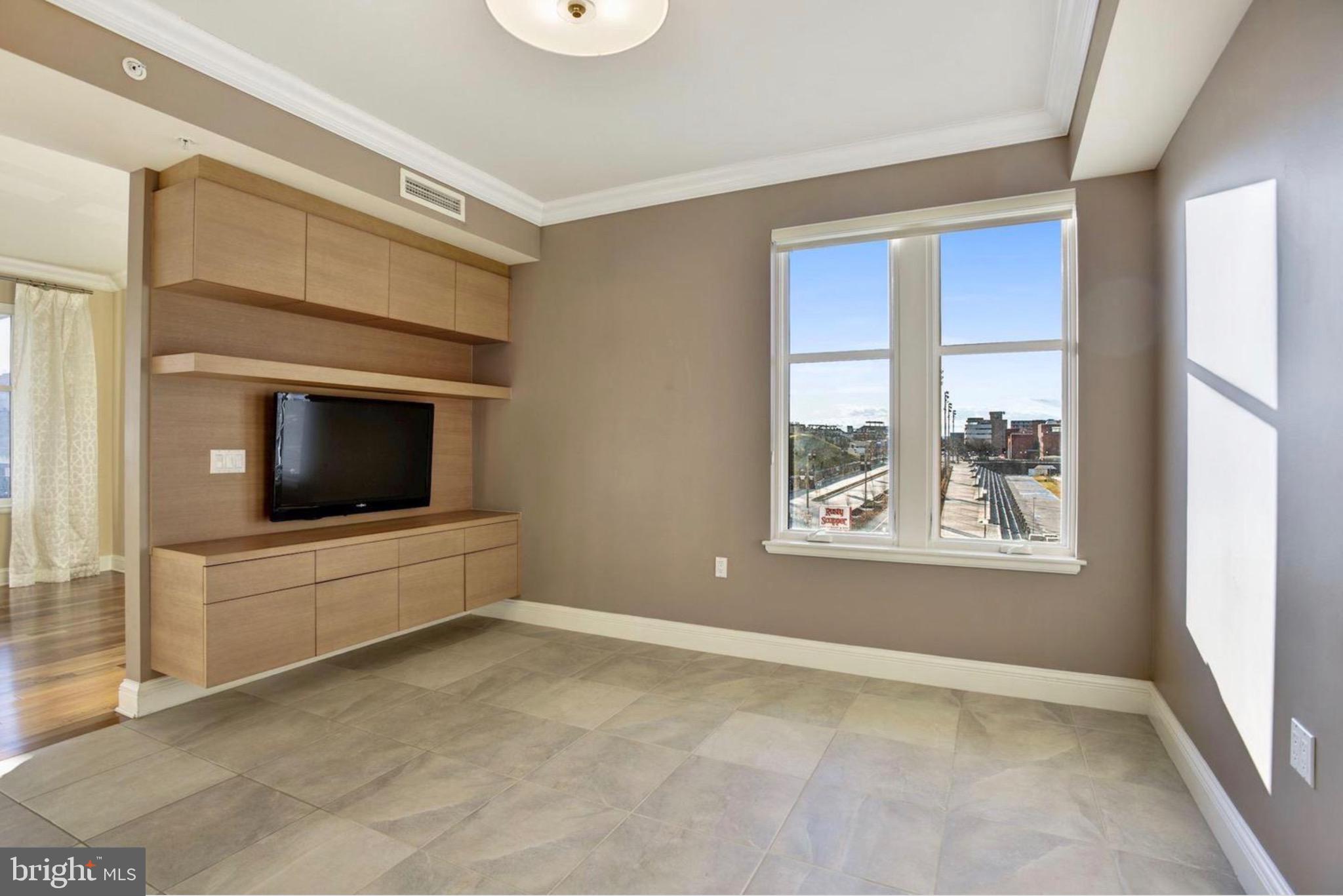 801 Key Highway, Unit 413 Baltimore, MD 21230 - Photo 13 of 40 a view of an empty room with a window and a flat screen tv