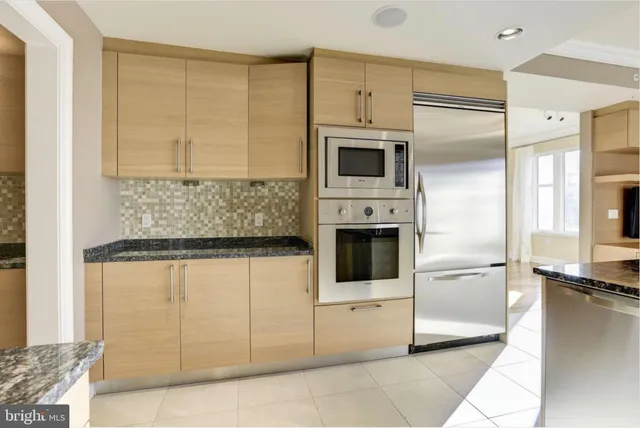 a kitchen with stainless steel appliances kitchen island granite countertop a refrigerator a stove and a sink