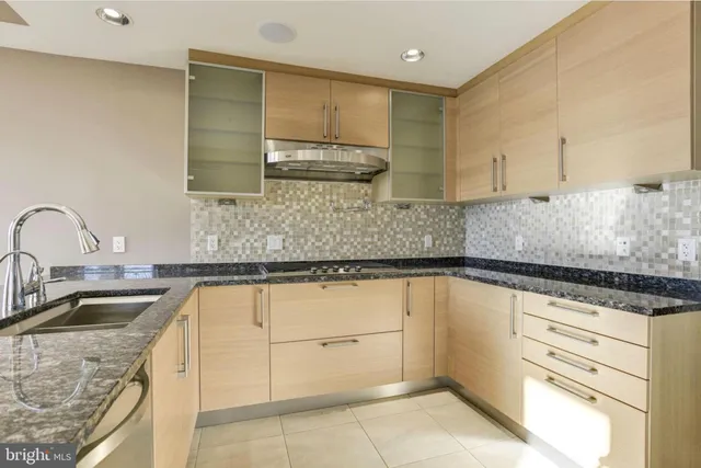 a kitchen with granite countertop a sink a stove and cabinets