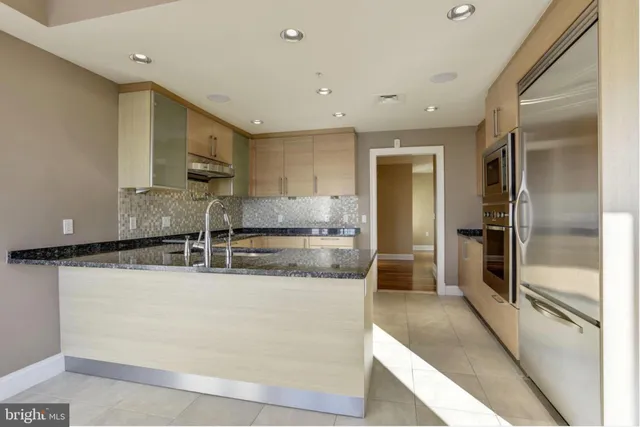 a large kitchen with stainless steel appliances granite countertop a refrigerator and a stove