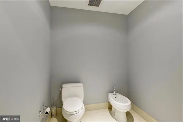 a white toilet sitting next to a white wall