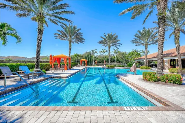 a view of swimming pool with a lounge chair and palm trees