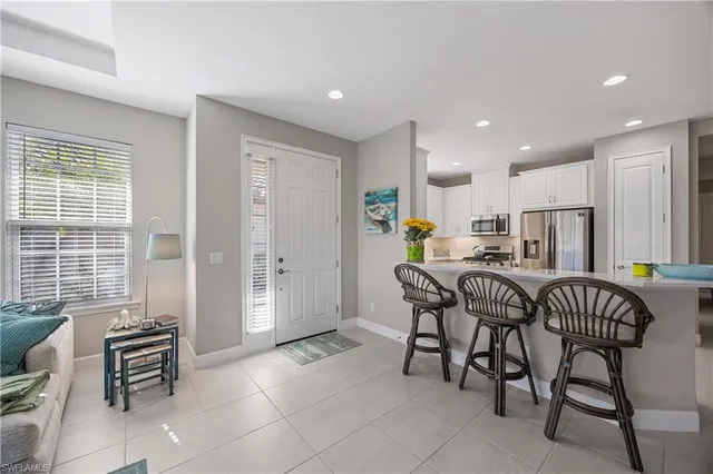 a kitchen with granite countertop a dining table chairs and a refrigerator