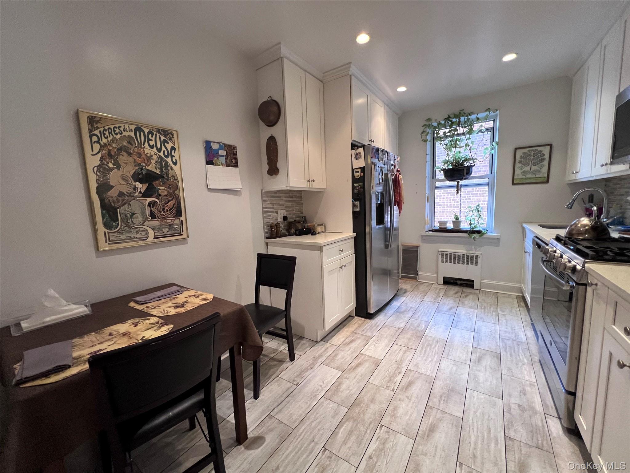 2080 Barnes Avenue, Unit 5C Bronx, NY 10462 - Photo 2 of 13 a kitchen with a table chairs refrigerator and sink