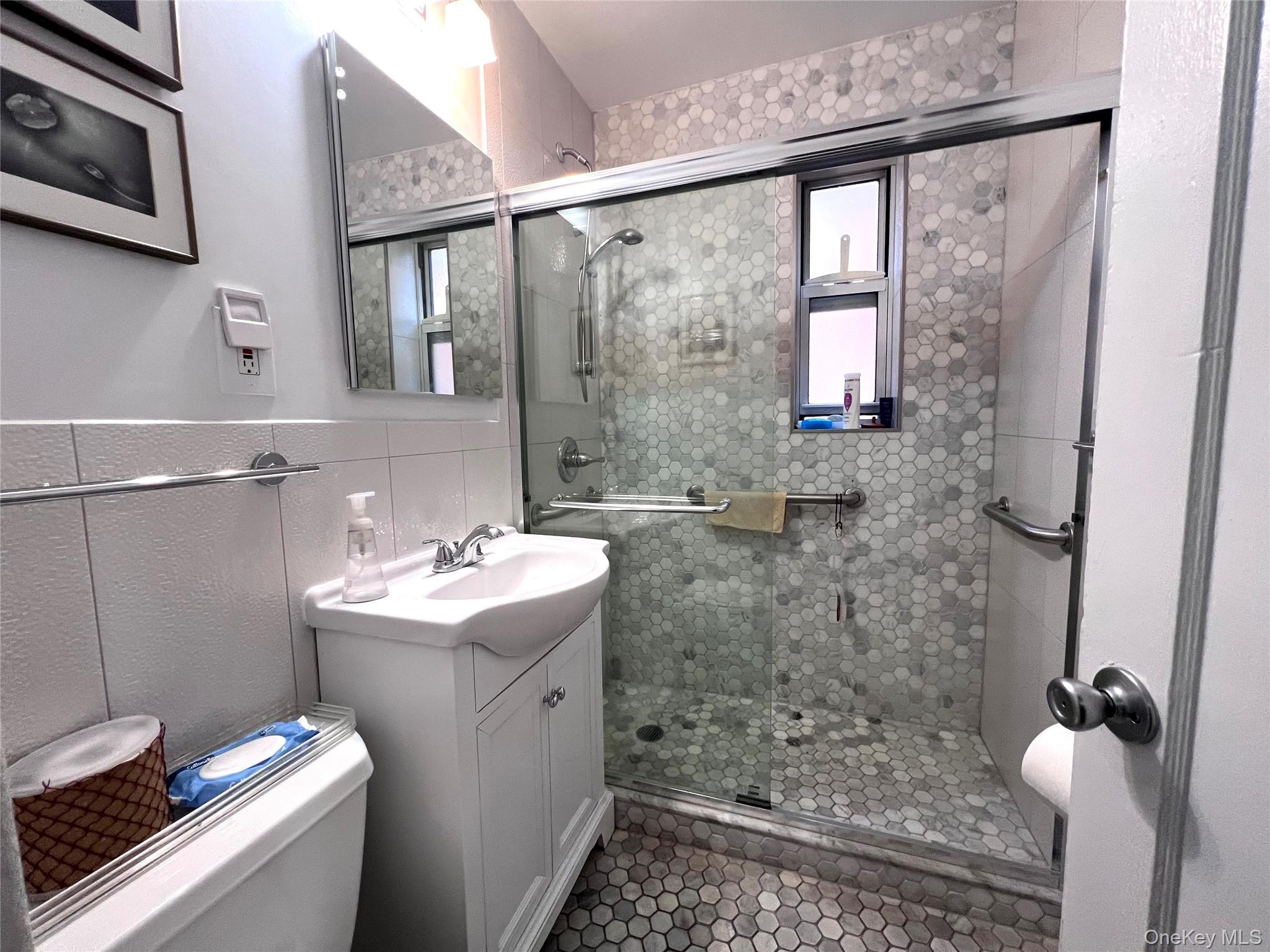 2080 Barnes Avenue, Unit 5C Bronx, NY 10462 - Photo 5 of 13 a bathroom with a sink mirror and shower