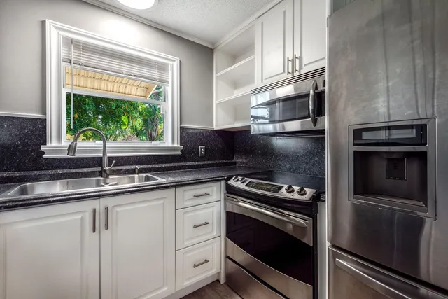 a kitchen with white cabinets appliances and a window
