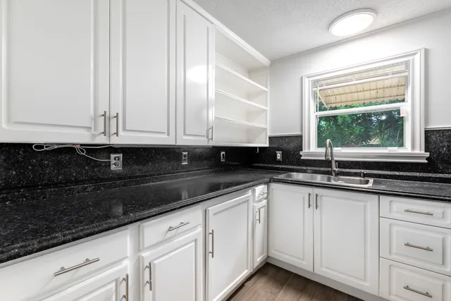 a kitchen with granite countertop white cabinets and sink