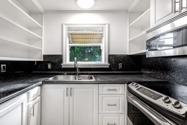 a kitchen with stainless steel appliances granite countertop a sink a stove and a granite counter tops