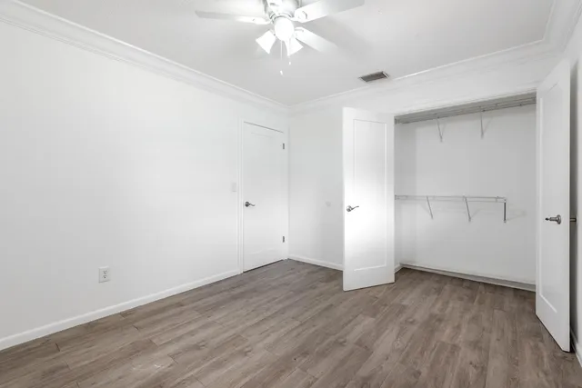 an empty room with wooden floor and ceiling fan
