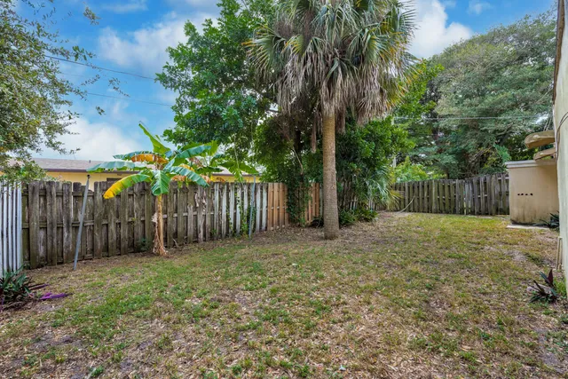 a view of a backyard with large trees and wooden fence