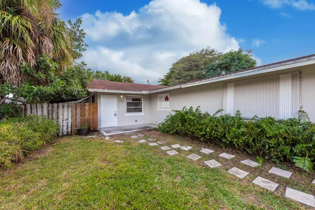 a backyard of a house with plants and trees with wooden fence