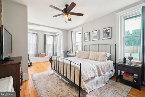 a bedroom with a bed a couch and a flat tv screen on dresser