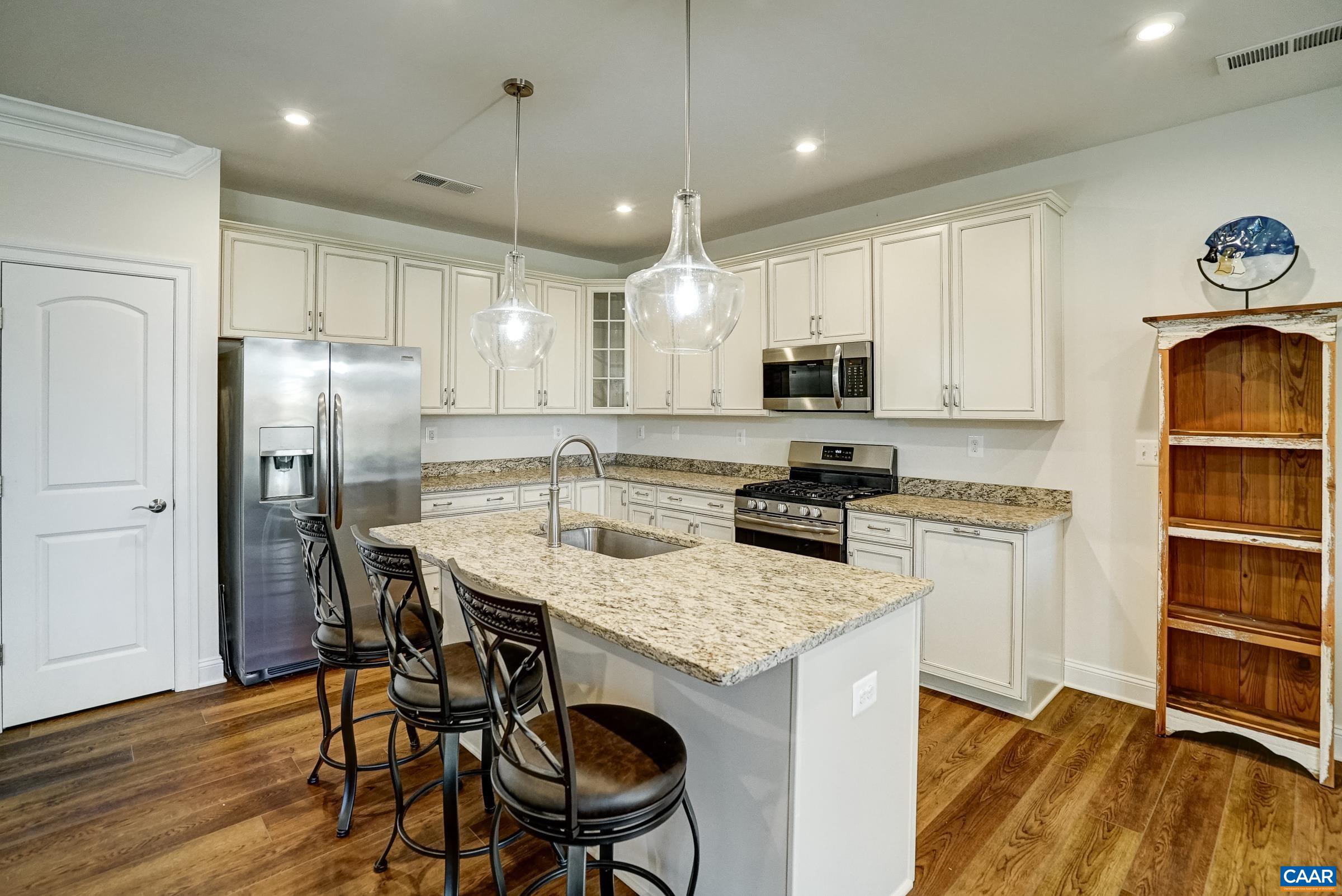 146 Timber Ridge Lane Zion Crossroads, VA 22942 - Photo 12 of 31 a kitchen with stainless steel appliances granite countertop a stove a refrigerator a microwave a sink and a dining table with wooden floor