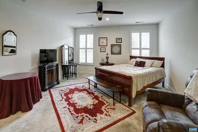 a living room with a bed furniture flat screen tv and a window