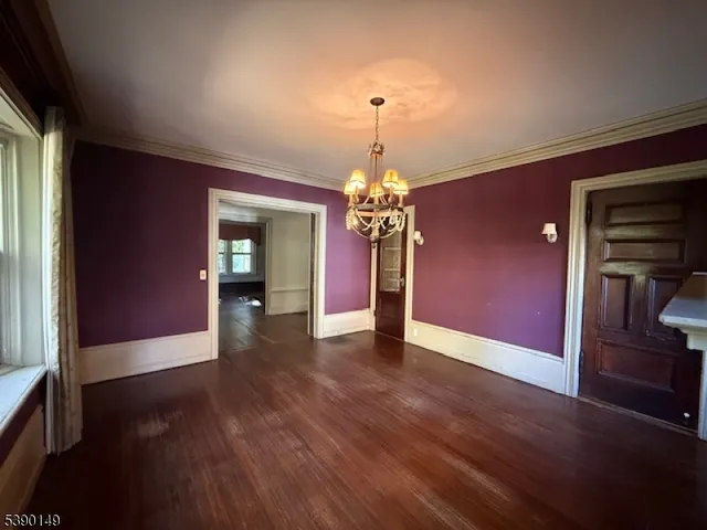 a view of a livingroom with wooden floor a chandelier and windows