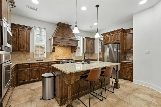 a kitchen with stainless steel appliances granite countertop a sink a stove and a refrigerator