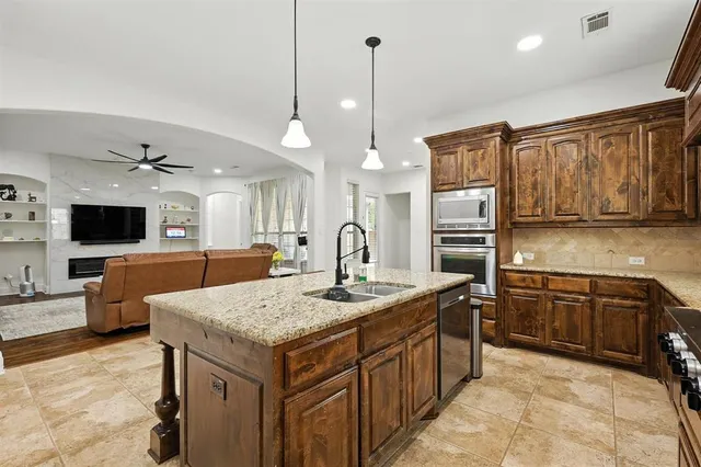a kitchen with stainless steel appliances granite countertop a sink refrigerator and cabinets