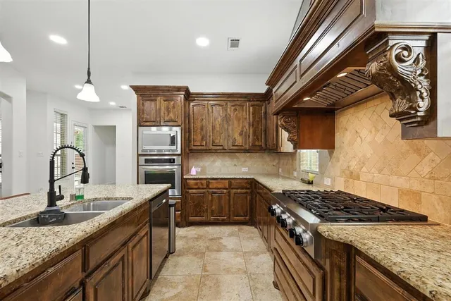 a kitchen with granite countertop a sink stainless steel appliances and cabinets