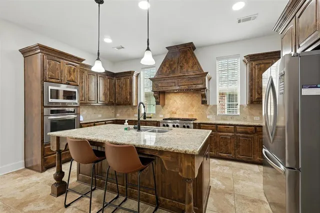 a kitchen with stainless steel appliances granite countertop a stove a refrigerator and a sink