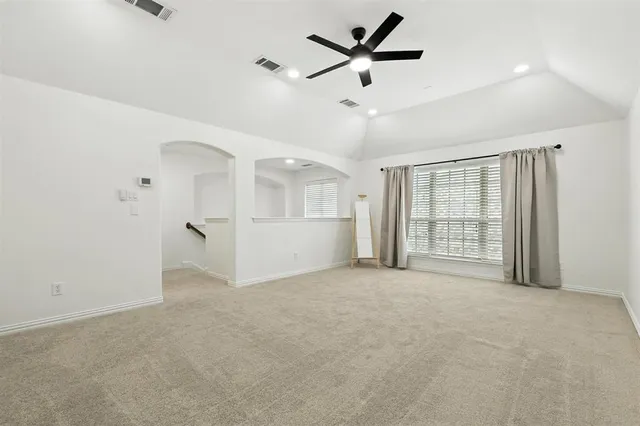an empty room with windows and ceiling fan