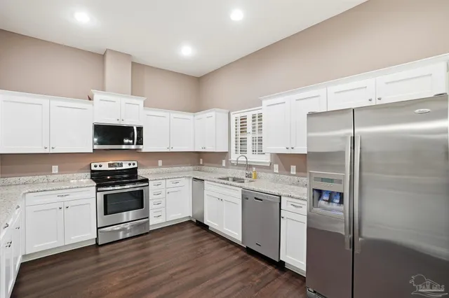 a kitchen with a sink stainless steel appliances and white cabinets