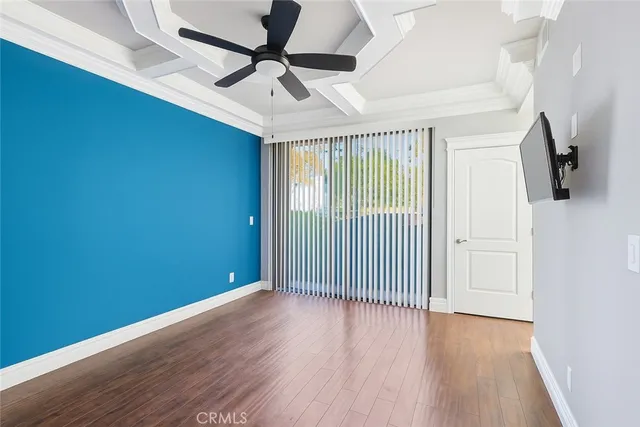 an empty room with wooden floor chandelier fan and windows