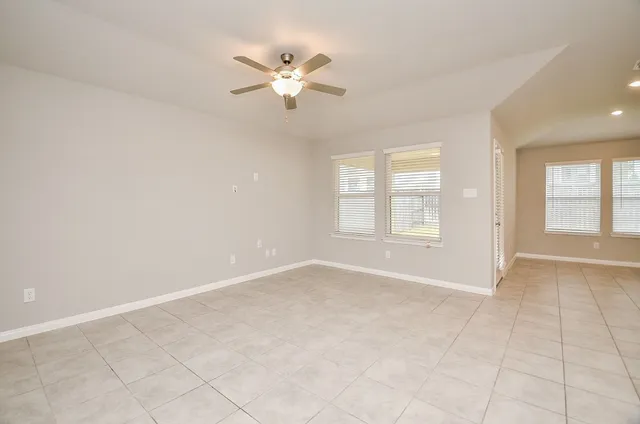 an empty room with windows and fan