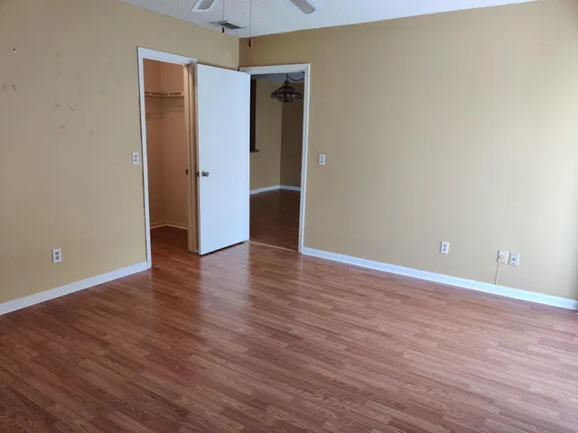 a view of an empty room with wooden floor and closet