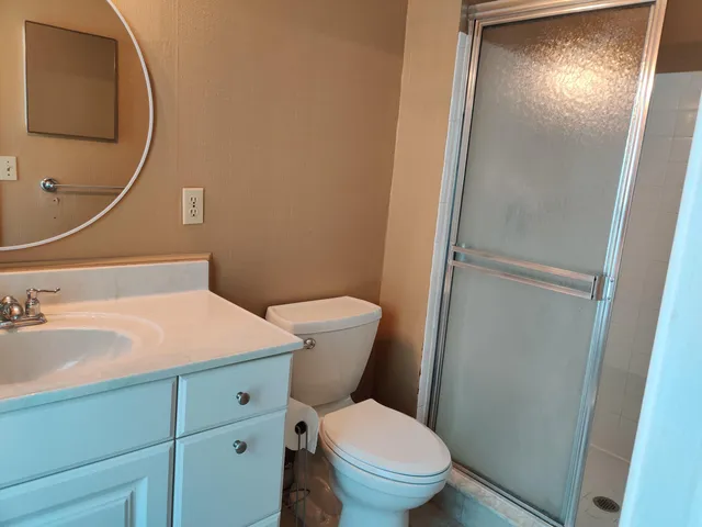 a bathroom with a granite countertop toilet sink and mirror