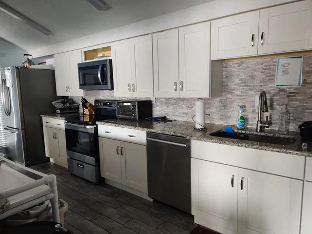 a kitchen with a sink white cabinets and stainless steel appliances