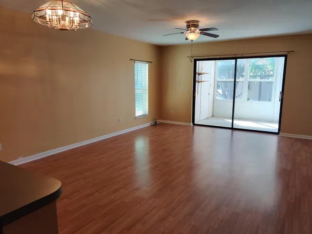 a view of empty room with wooden floor and fan