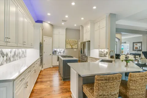 a large kitchen with kitchen island a stove a sink a dining table and chairs with wooden floor