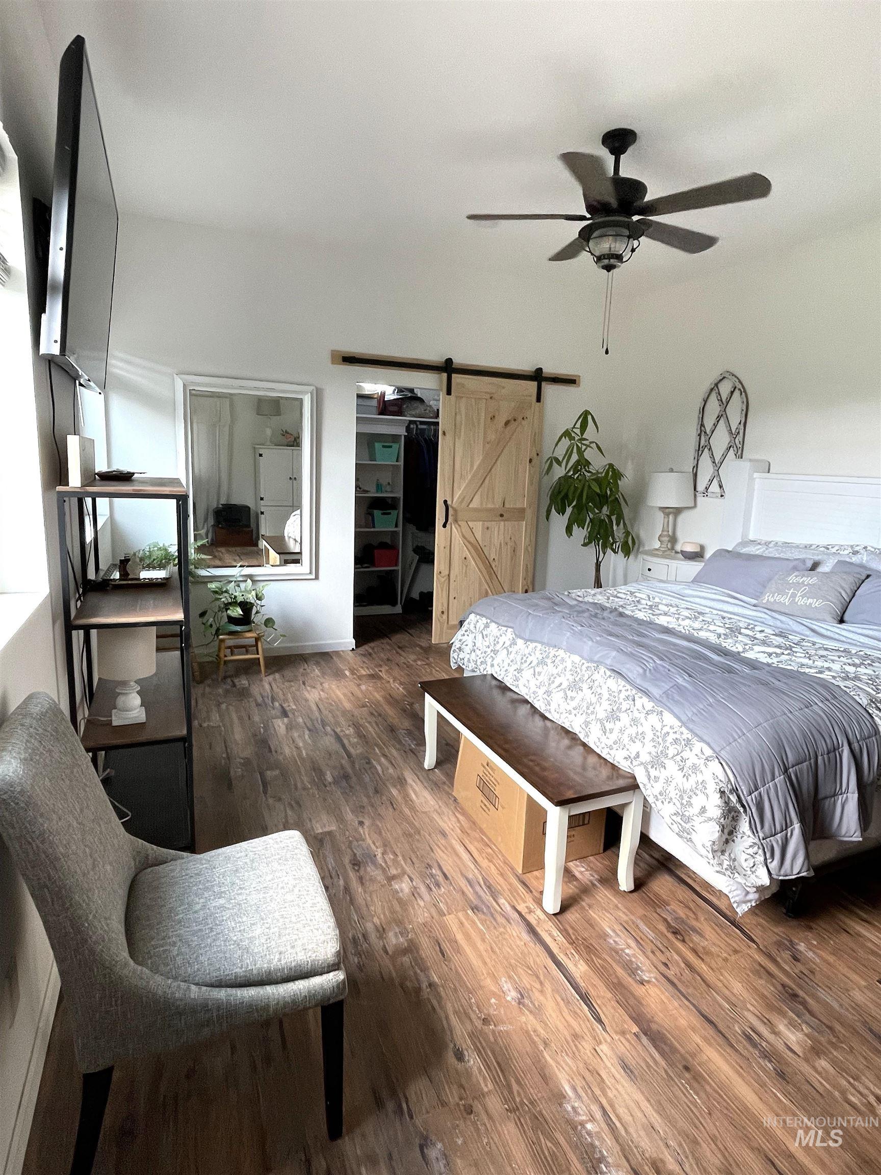 12733 South Five Mile Road Kuna, ID 83634 - Photo 12 of 21 Bedroom featuring a barn door, wood finished floors, a walk in closet, and ceiling fan