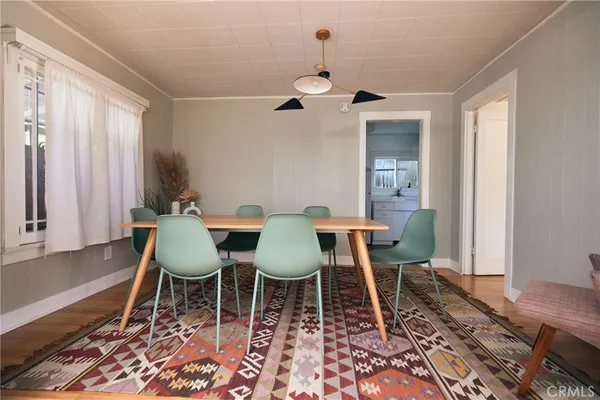 a dining room with wooden floor a chandelier a wooden table and chairs