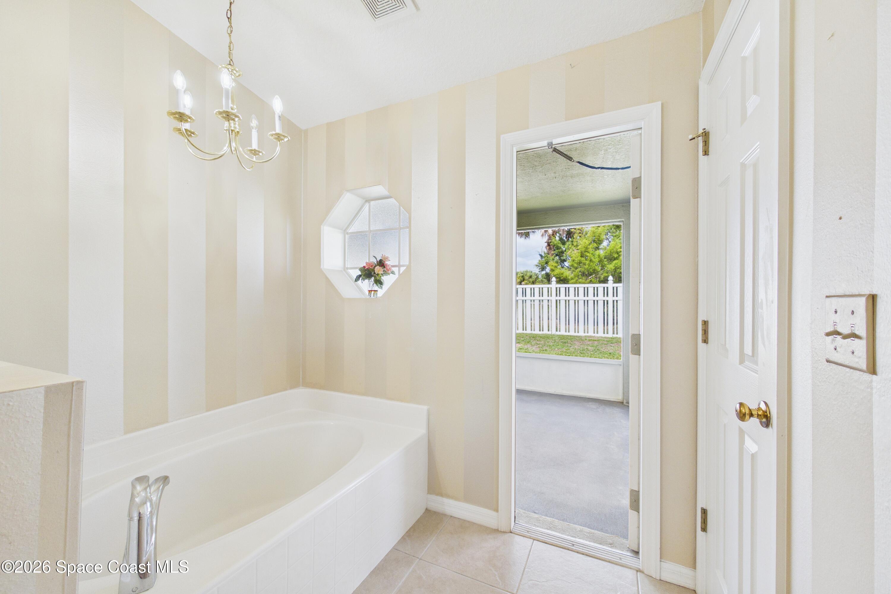 183 Stony Point Drive Sebastian, FL 32958 - Photo 18 of 27 a bathroom with a bathtub a shower and a chandelier