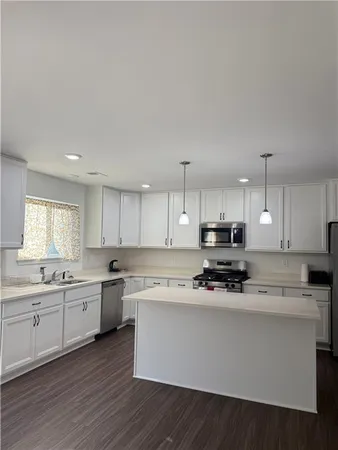 a kitchen with stainless steel appliances white cabinets a sink a stove a microwave and wooden floors