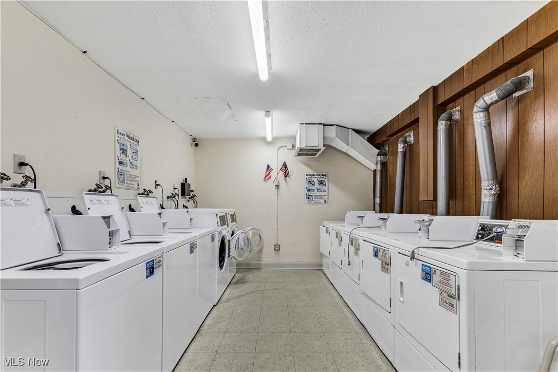 6640 Pearl Road, Unit 104 Cleveland, OH 44130 - Photo 22 of 31 Shared laundry room with washer and clothes dryer, light floors, wood walls, a textured ceiling, and baseboards