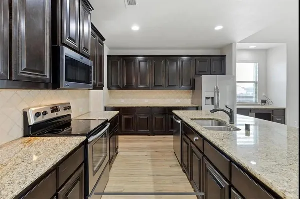 a kitchen with stainless steel appliances granite countertop a sink stove and refrigerator