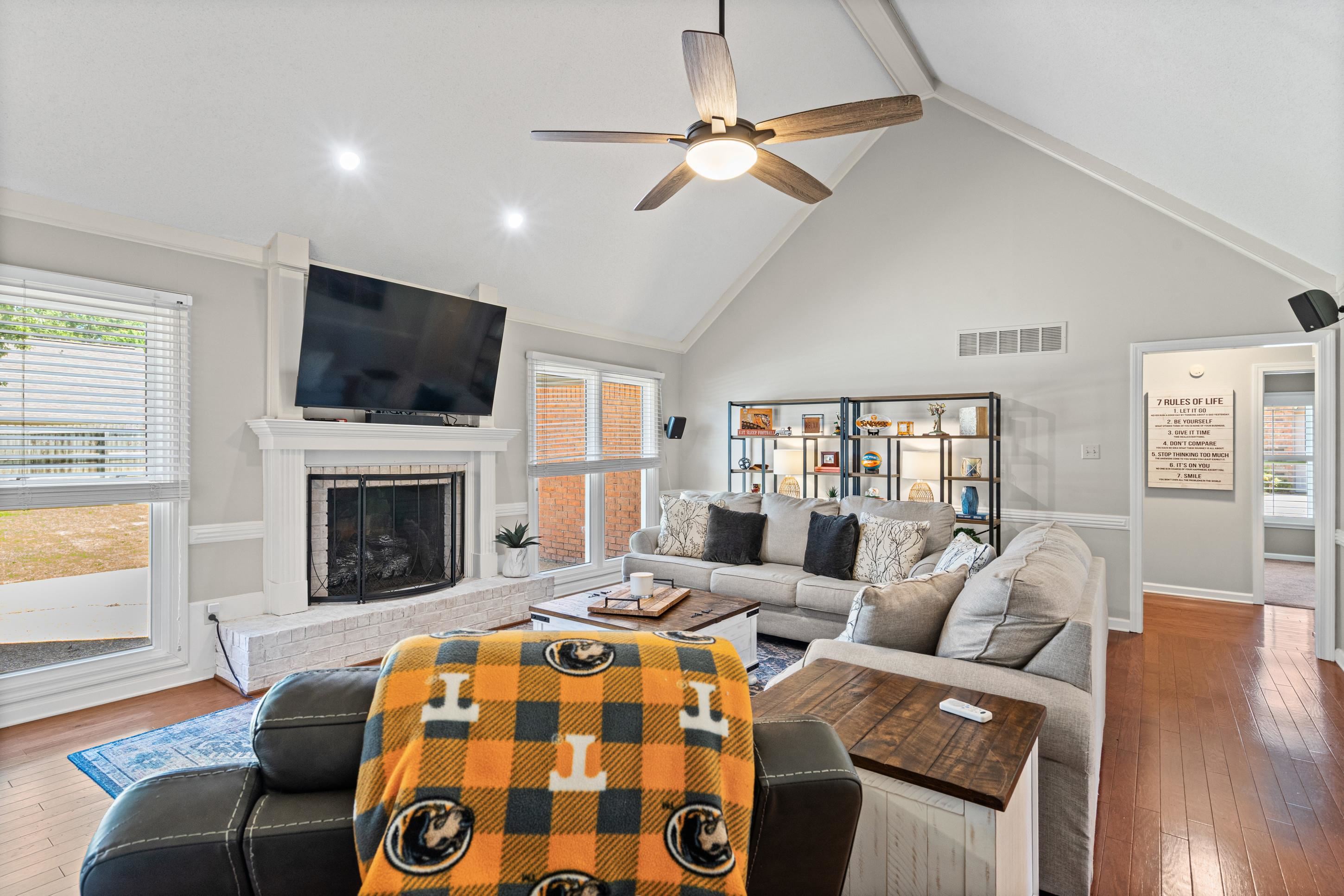 304 Spring Mill Road Collierville, TN 38017 - Photo 12 of 32 Vaulted ceiling living area featuring a white brick fireplace with a mantle, wood-finish flooring, and a ceiling fan