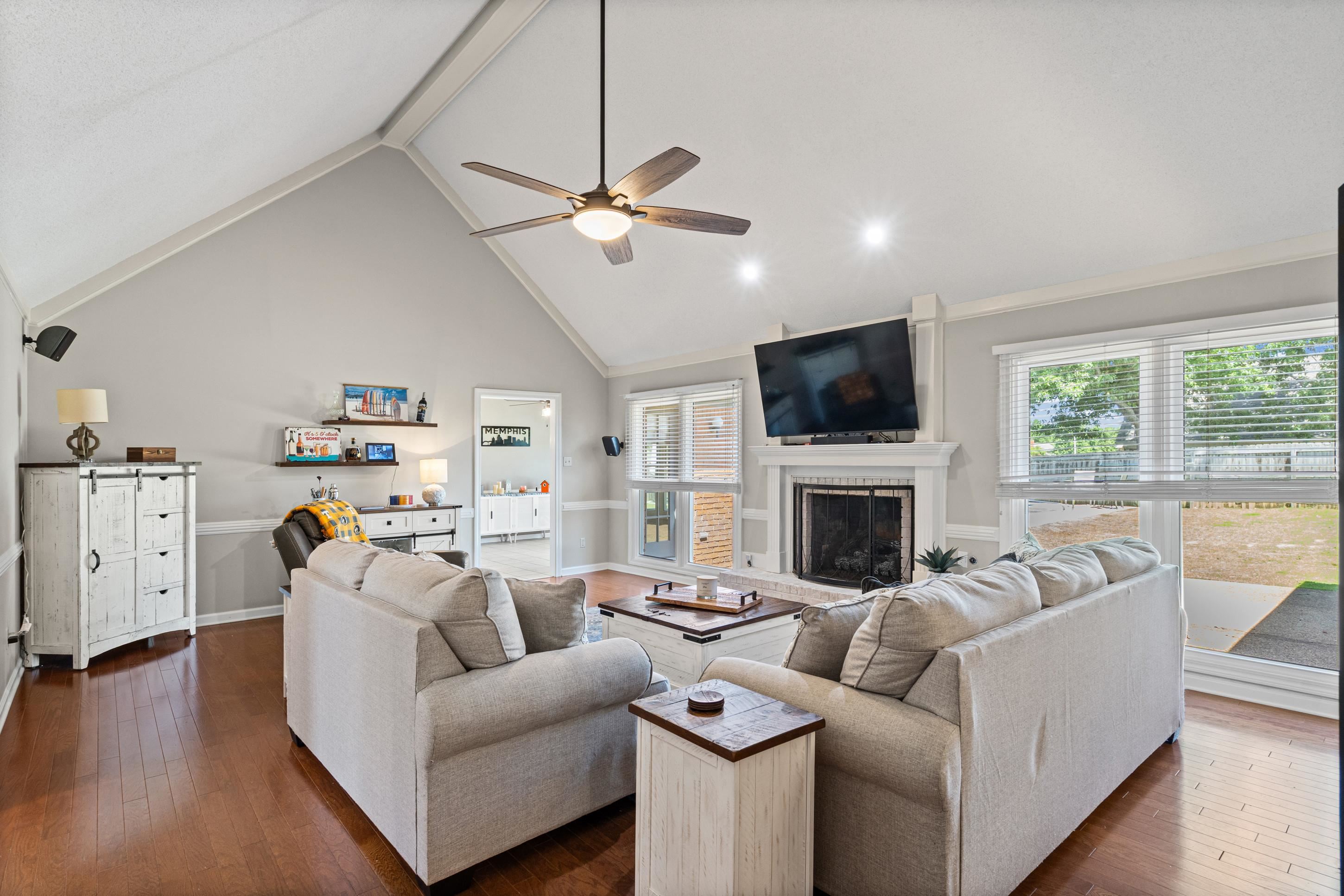 304 Spring Mill Road Collierville, TN 38017 - Photo 13 of 32 Living area featuring vaulted ceilings with exposed beams, wood-finish flooring, a fireplace with white mantel, a ceiling fan, and large windows
