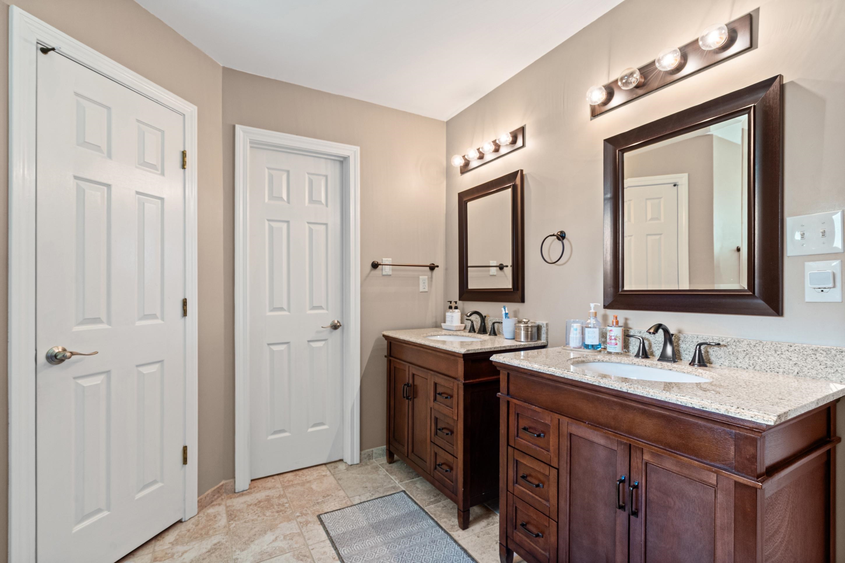 304 Spring Mill Road Collierville, TN 38017 - Photo 16 of 32 Bathroom featuring dual vanities with wood cabinetry, light-toned countertops, undermount sinks, bronze faucets, and framed mirrors