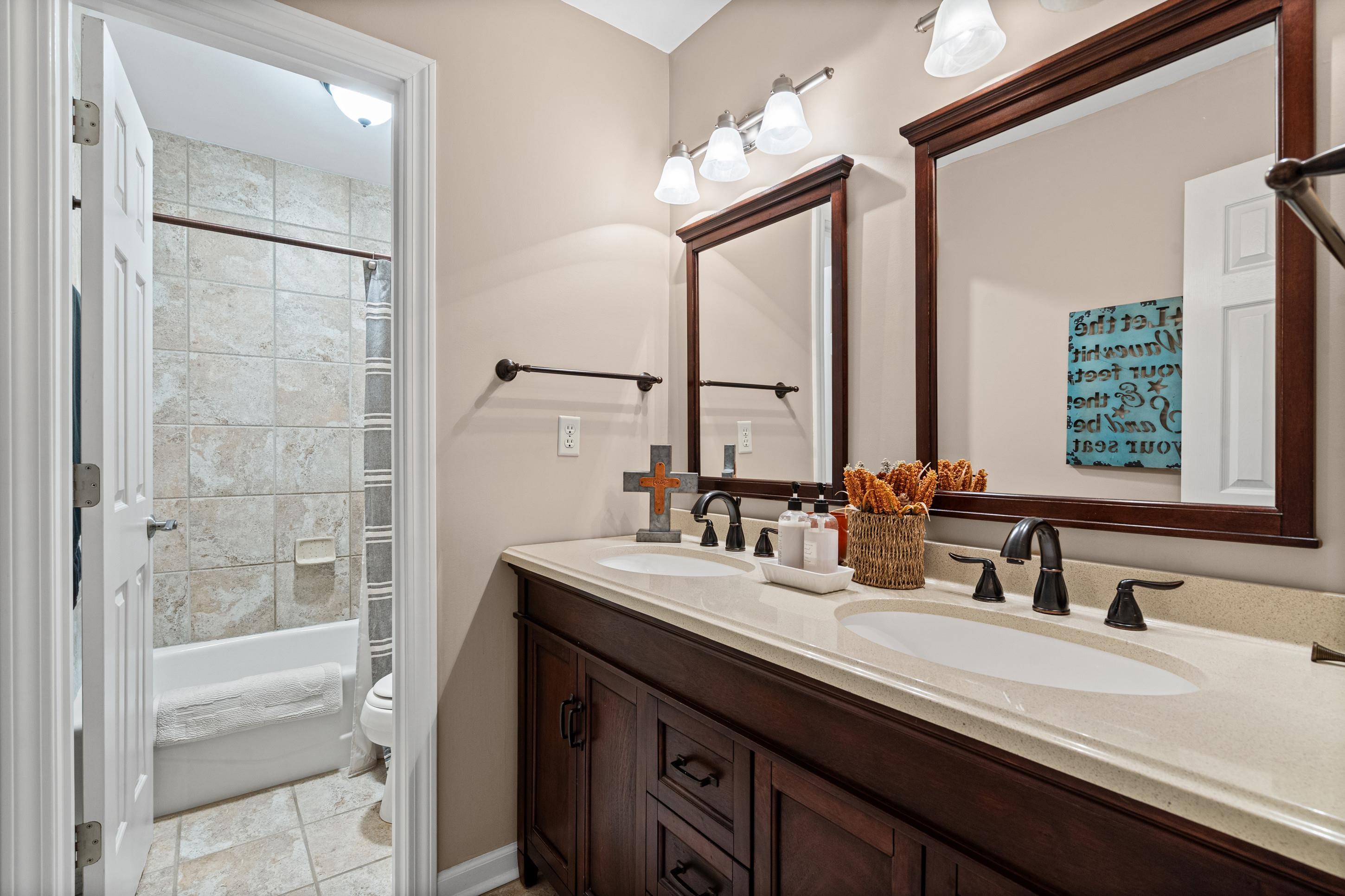 304 Spring Mill Road Collierville, TN 38017 - Photo 19 of 32 Bathroom featuring a dual vanity with undermount sinks, bronze-finish faucets, a light-toned countertop, and dark wood cabinetry