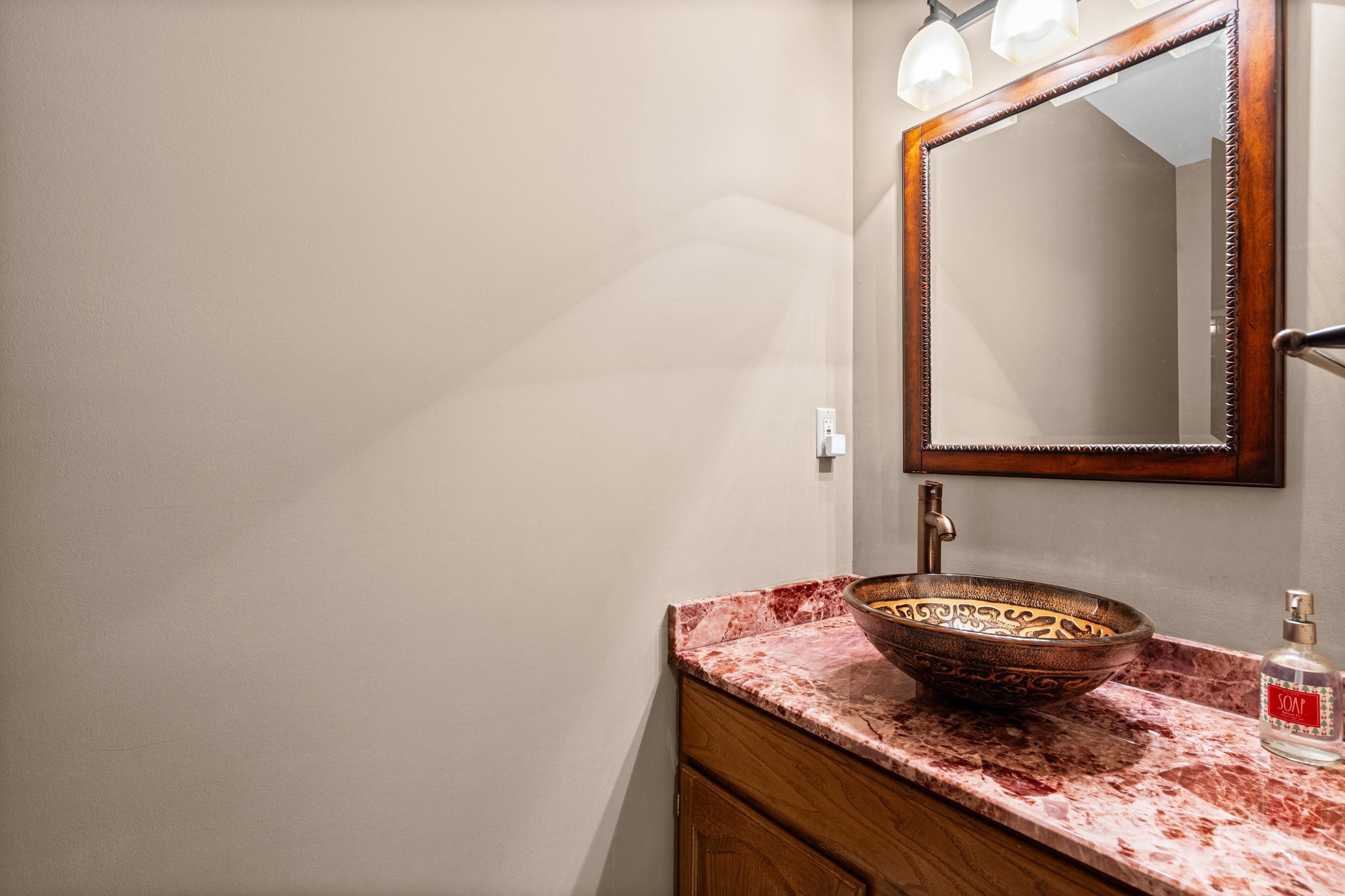 304 Spring Mill Road Collierville, TN 38017 - Photo 22 of 32 Vanity featuring a vessel sink with an ornate interior, a wood-finish cabinet, and a red-veined countertop
