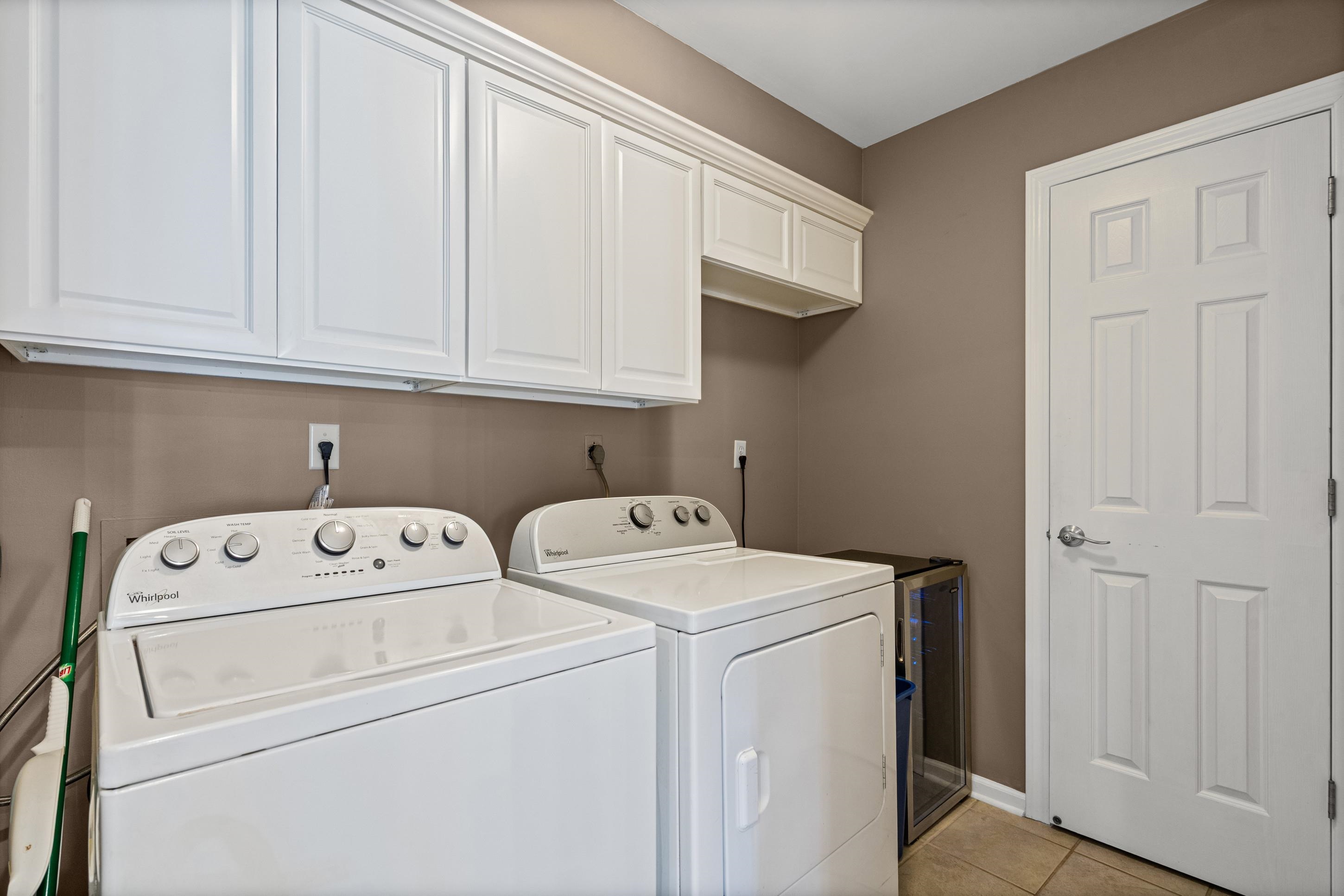 304 Spring Mill Road Collierville, TN 38017 - Photo 23 of 32 Laundry area featuring white cabinetry, a built-in shelf, tiled flooring, and a white paneled door with a brushed chrome handle