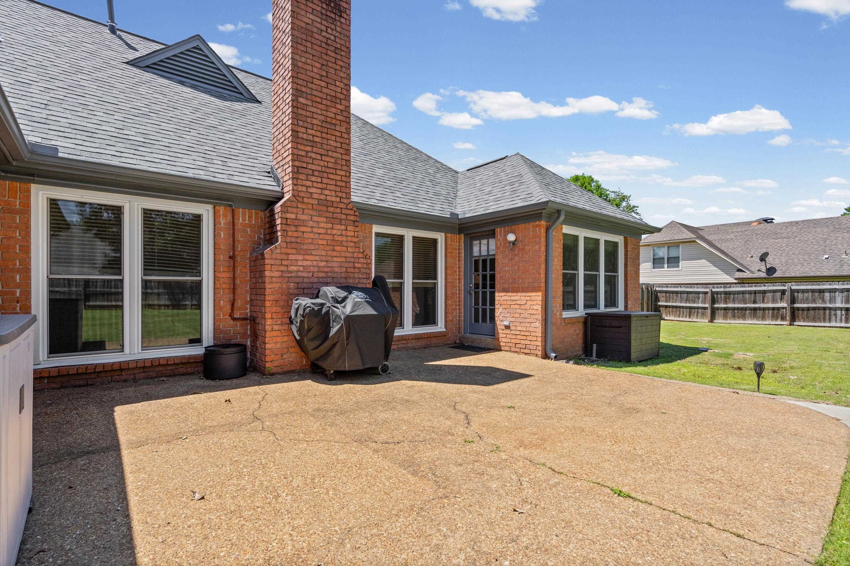 304 Spring Mill Road Collierville, TN 38017 - Photo 24 of 32 Expansive concrete patio with a brick exterior, multiple windows, and a shingle roof