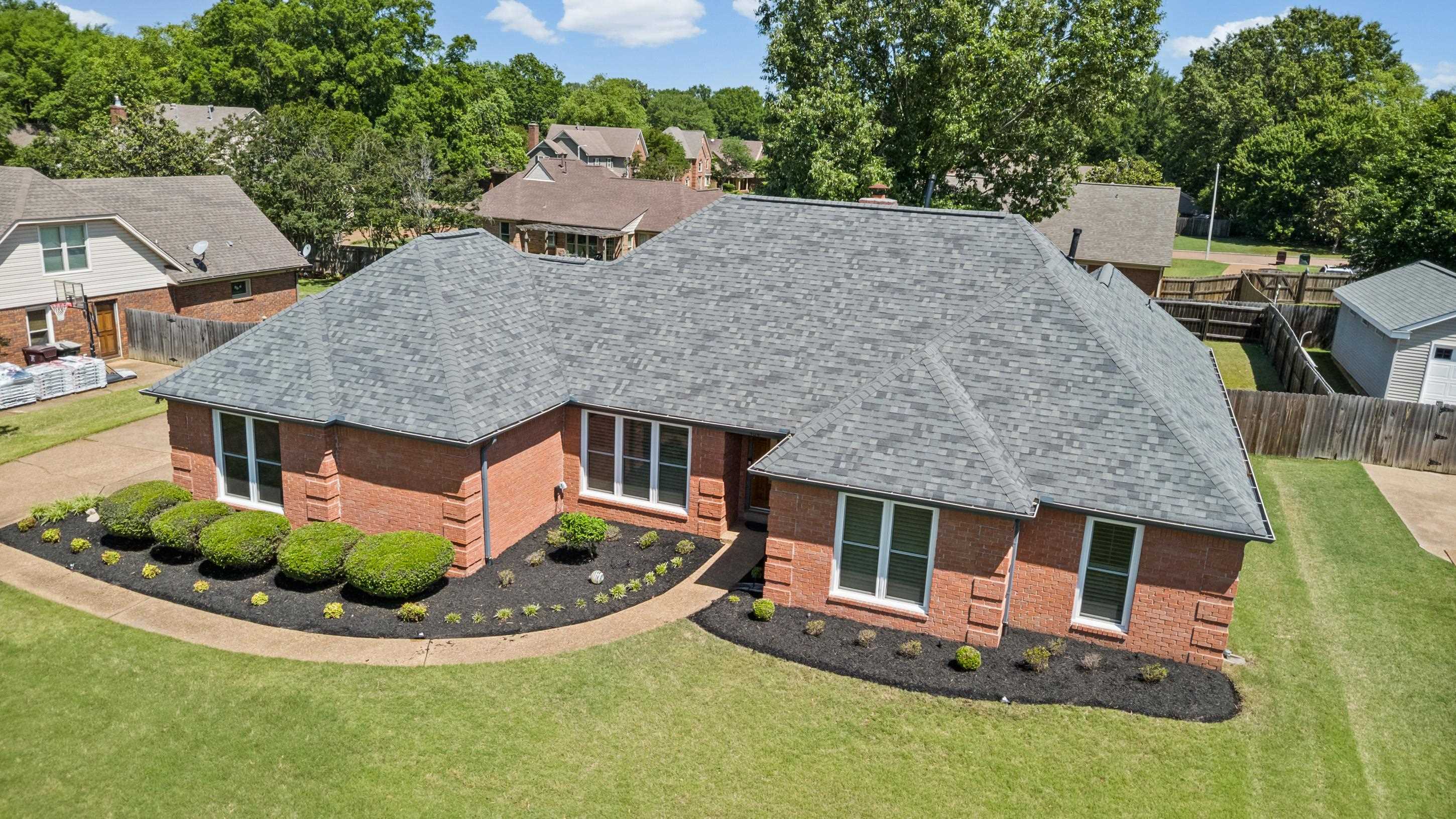 304 Spring Mill Road Collierville, TN 38017 - Photo 30 of 32 Brick exterior residence featuring a gray shingle roof, white-framed windows, and neatly mulched landscaping with established shrubs