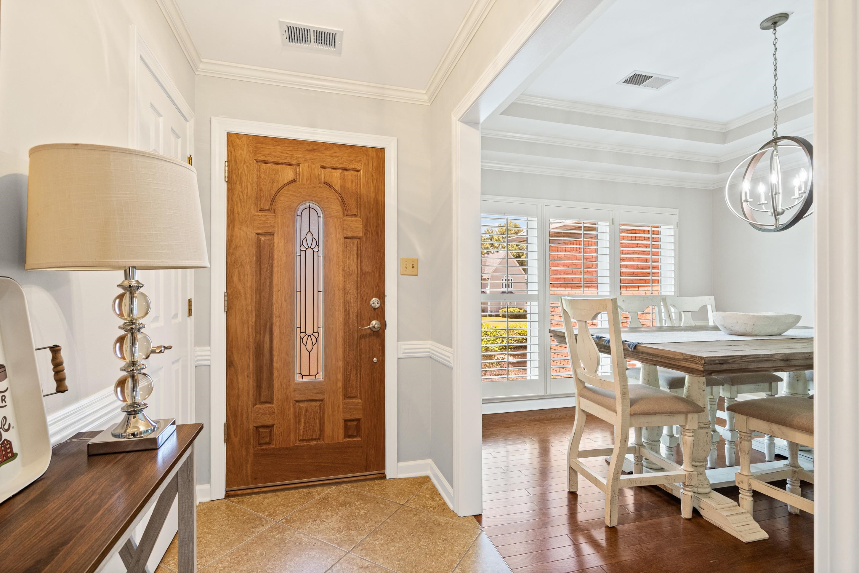 304 Spring Mill Road Collierville, TN 38017 - Photo 5 of 32 Entryway featuring a wood-panel door with decorative glass insert, tiled flooring, and a cased opening to an adjacent room