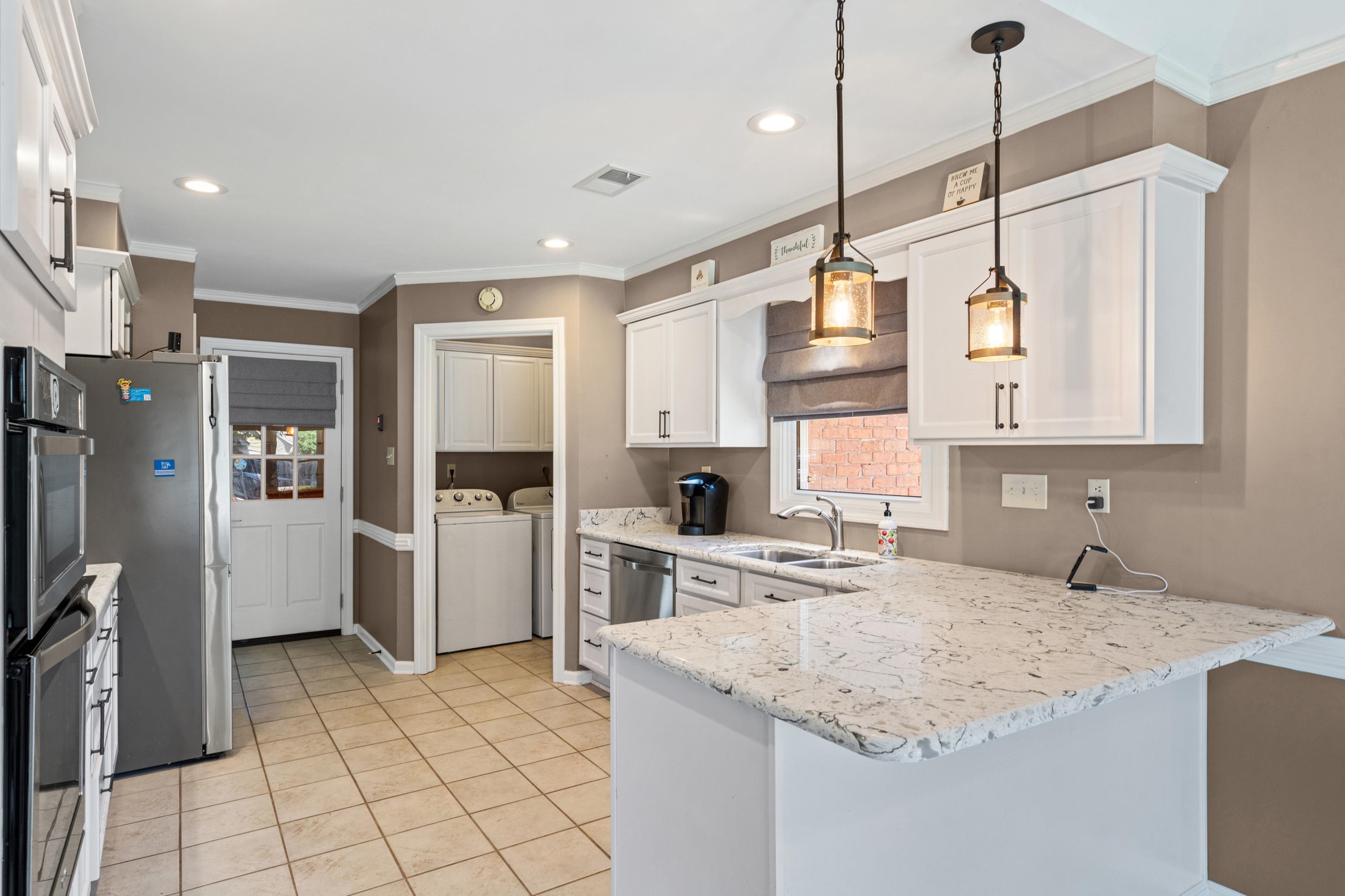 304 Spring Mill Road Collierville, TN 38017 - Photo 7 of 32 Kitchen featuring a breakfast bar, white cabinetry, integrated stainless steel appliances, pendant lighting, and light-toned tile flooring