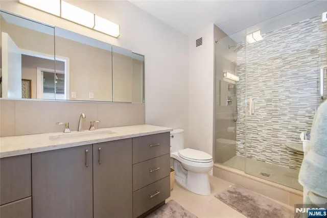 a bathroom with a sink a toilet a mirror and shower