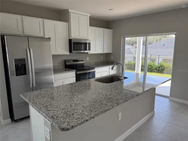 a kitchen with stainless steel appliances granite countertop a sink refrigerator and microwave